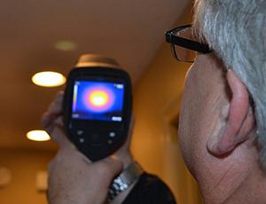 A Midwest Energy auditor uses an infrared camera to measure energy loss around ceiling lights during a whole-home energy audit.
